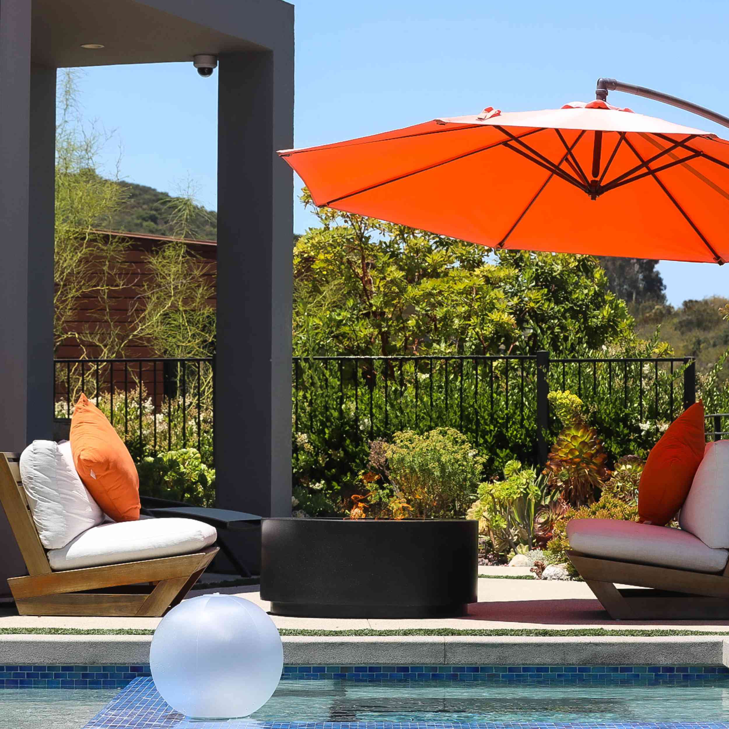 Oblica Black In open area with Orange umbrella beside pool