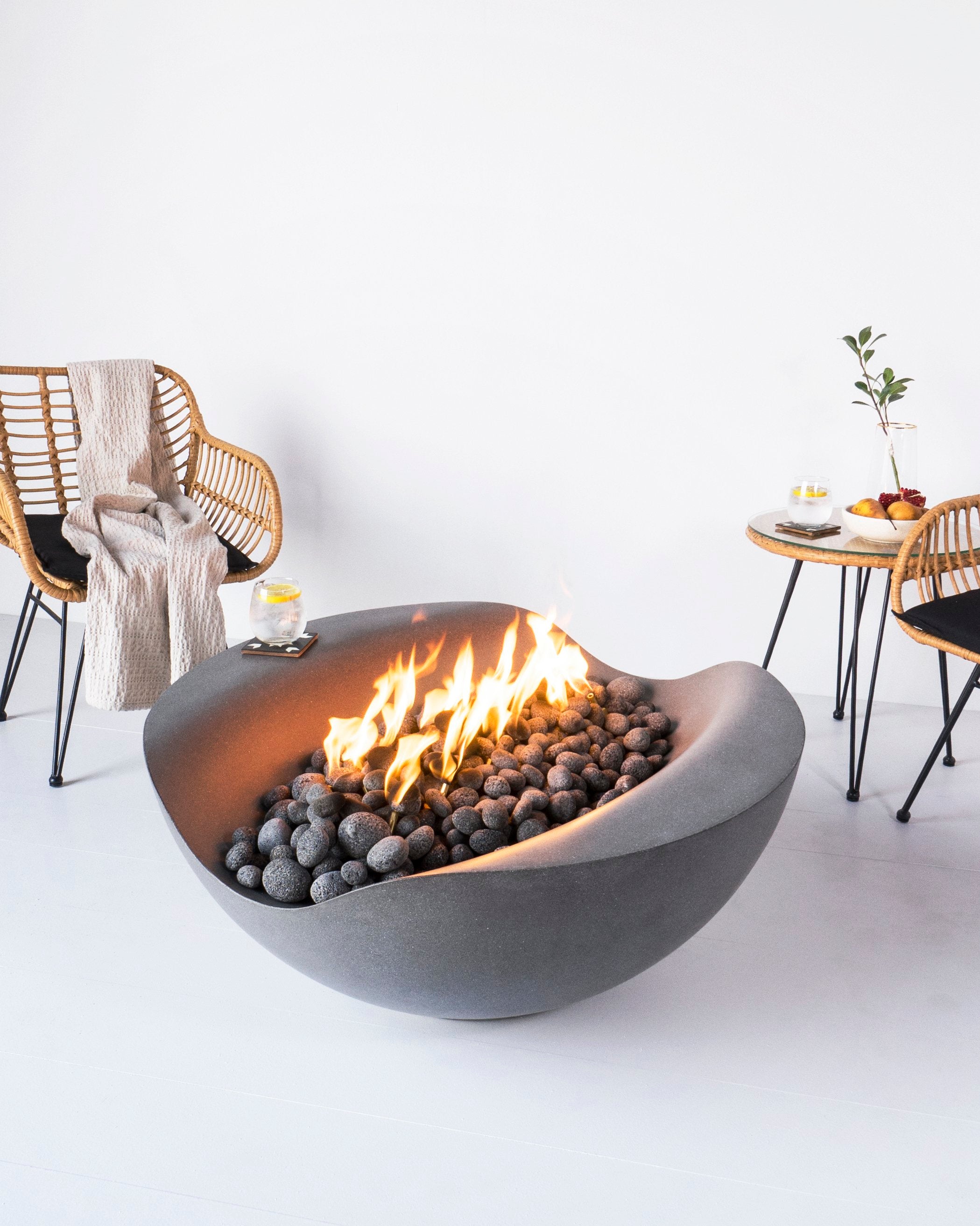 Lifestyle shot of Balance - a round concrete custom made fire pit in dark gray color